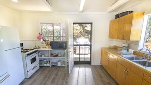 A kitchen with white cabinets, a stove, a microwave, and a sink.