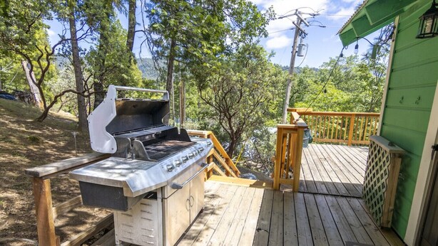 An outdoor grill on a wooden deck with a green building in the background.