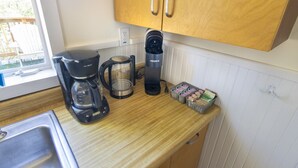 A kitchen with a coffee maker, a kettle, and a coffee grinder on the counter.