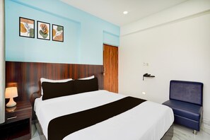 Ein Hotelzimmer mit Bett, Nachttisch, Lampe und einem Sessel.