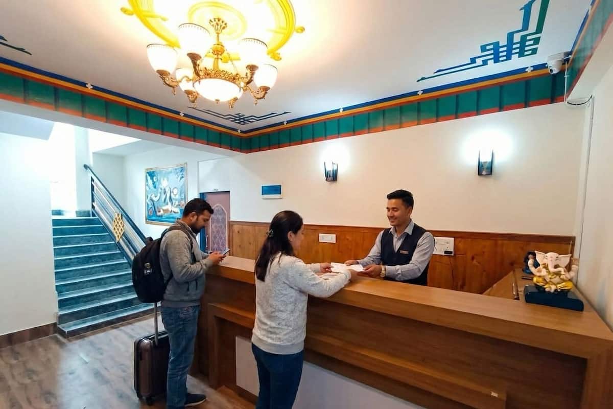 A reception desk with a wooden counter, a chandelier, and a staircase in the background.