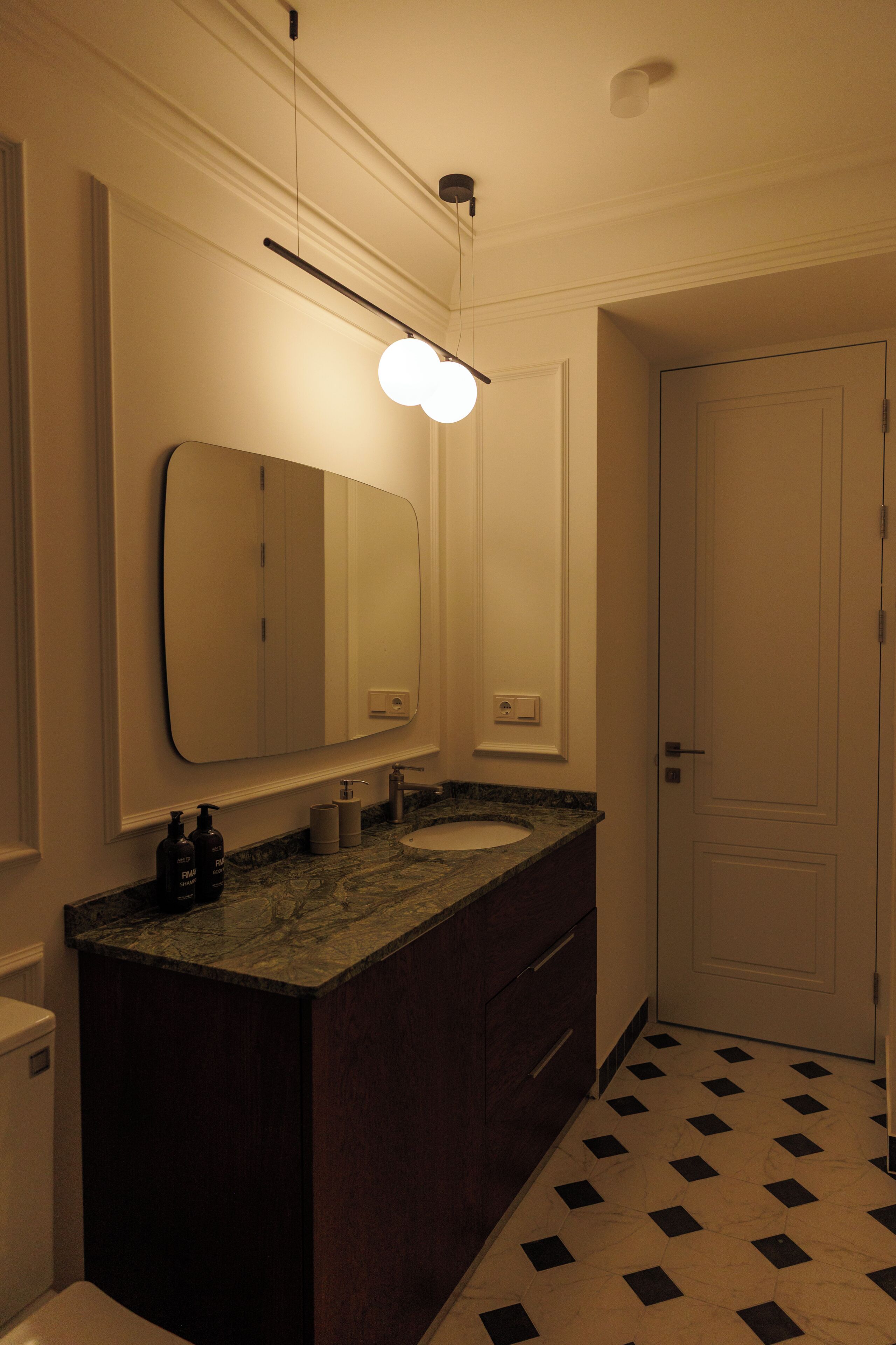 A bathroom with a large mirror, a sink, and a door.
