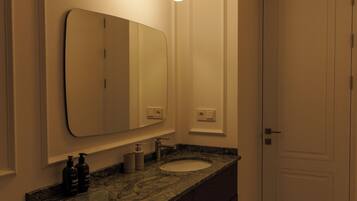 A bathroom with a large mirror, a sink, and a door.
