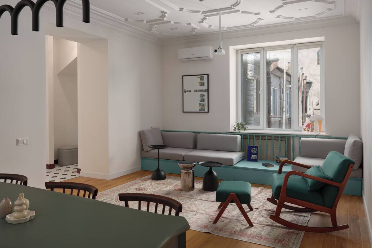 Una sala de estar moderna con un sofá, sillas, una mesa de comedor y un ventanal grande.