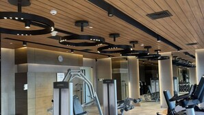 Un gimnasio con máquinas de cardio, equipo de levantamiento de pesas y suelo de madera.