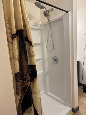 A shower with a handheld showerhead and a wall-mounted faucet.