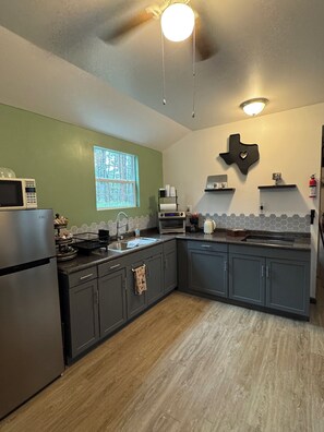A kitchen with a microwave, oven, sink, and cabinets.