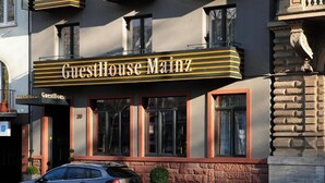 A building with a sign reading 'GuestHouse Mainz' and a parked car in front. - GuestHouse Mainz (Mainz)