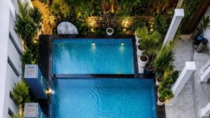 A rooftop swimming pool with a clear blue water surface, surrounded by lush greenery and white railings. - Jarokha Haveli  (Udaipur)