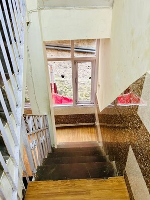 A staircase leading to a window with a view of a courtyard. - Shorya Regency Circular Road (Shimla)