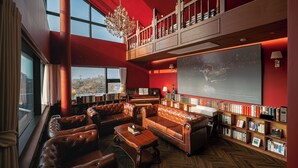 A library with leather sofas, a piano, bookshelves, and a large painting.