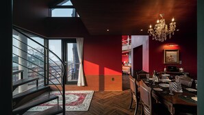 A modern interior with a dining area, a chandelier, and a view through large windows.