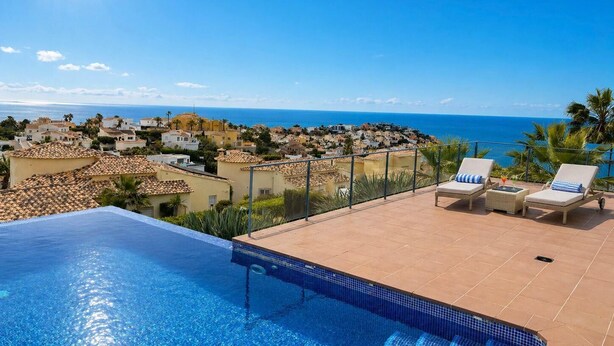 Piscina con sillones de descanso y vista a un pueblo costero.