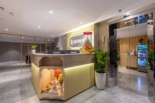 Una recepción de hotel con un adorno navideño, una pantalla digital y un refrigerador lleno de bebidas.