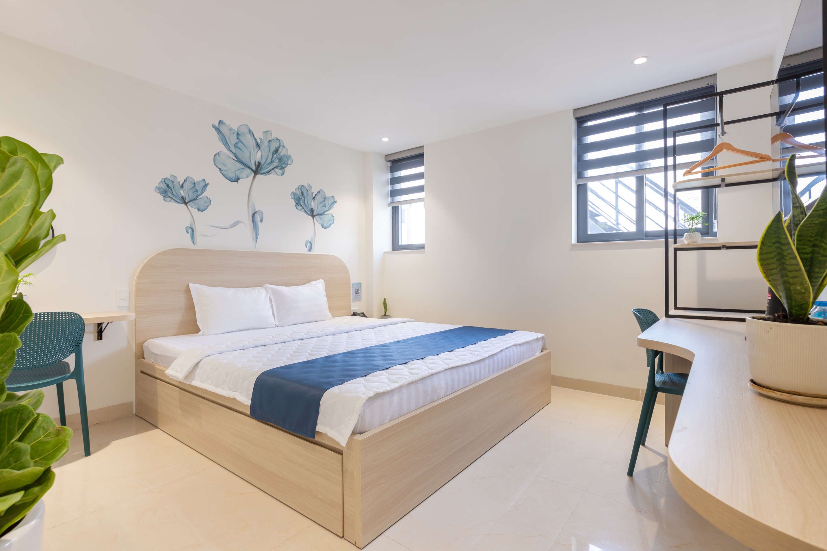 Un dormitorio moderno con una cama de madera, un escritorio y una planta en maceta.