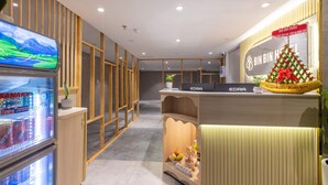 A hotel reception area with a reception desk, a refrigerator with beverages, and a Christmas tree decoration. - Bin Bin Hotel 18 - Near Thu Thiem Villa Park (Ho Chi Minh City)
