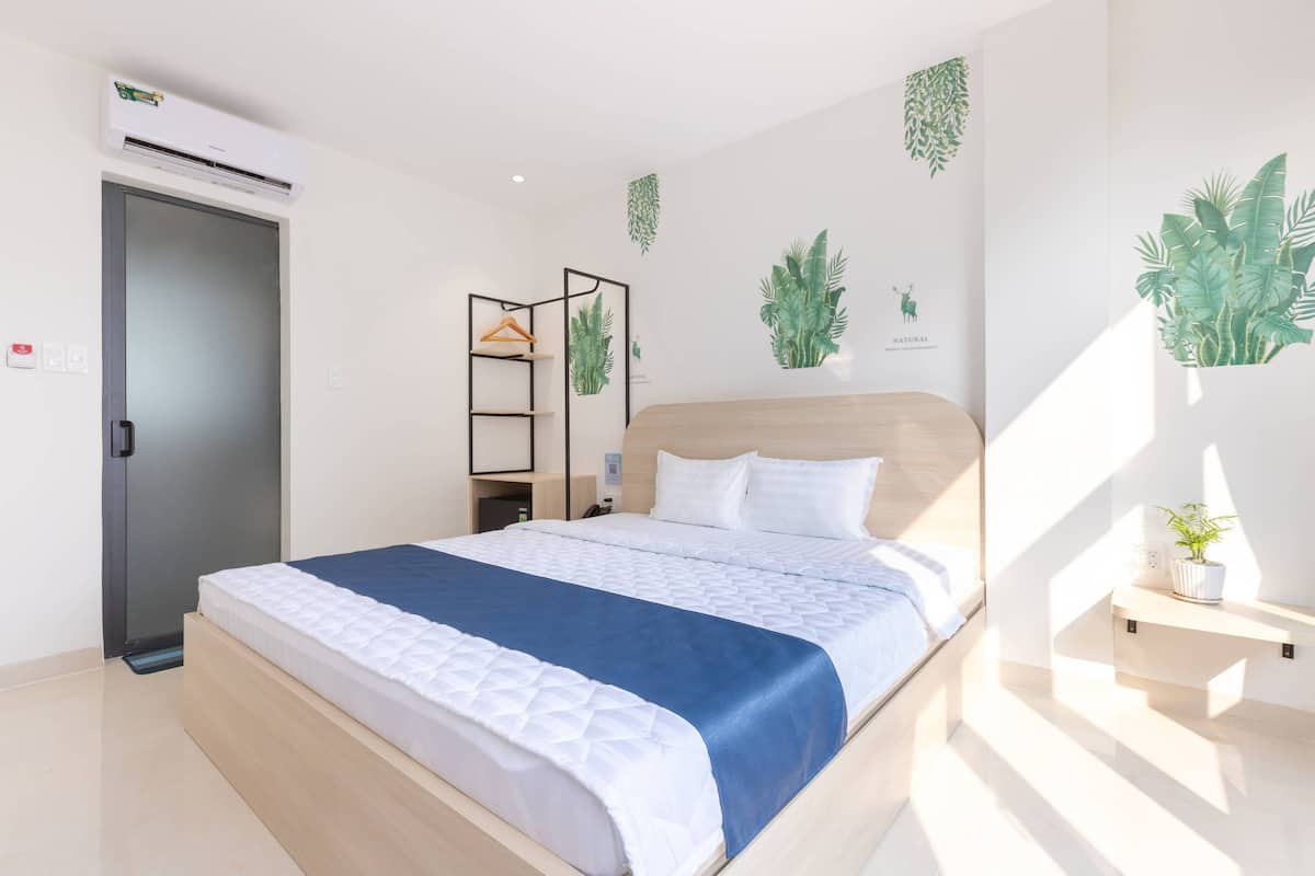 Ein modernes Schlafzimmer mit Bett, Kleiderschrank, Ablagefläche mit Pflanze und Wand-Klimaanlage.