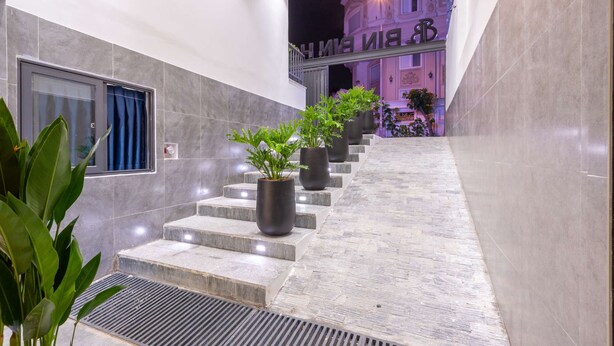 A hotel lobby with a staircase, potted plants, and a sign above the stairs. - Bin Bin Hotel 18 - Near Thu Thiem Villa Park (Ho Chi Minh City)
