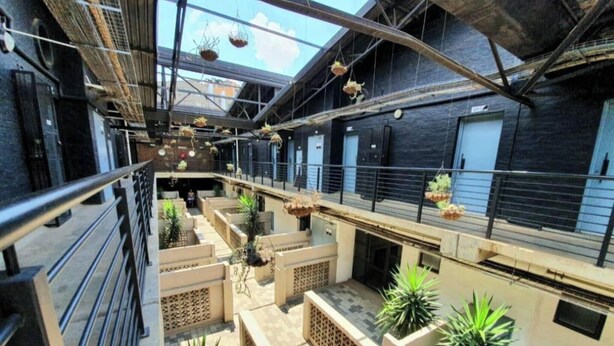 A multi-level atrium with hanging planters, a metal railing, and a staircase.