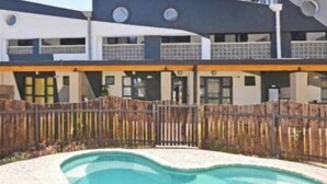 A modern building with a swimming pool, a wooden fence, and a balcony.