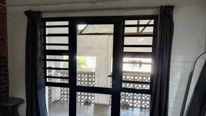A room with a sliding glass door leading to an outdoor area with a concrete floor and a metal fence.