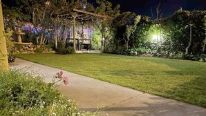 A well-maintained garden with a pathway leading to a gazebo, surrounded by lush greenery and flowering plants. - Spacious 4BR Family Home, 5 Min to Rockingham Foreshore (Rockingham)