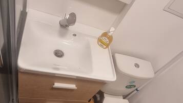 Een badkamer met een wit wastafel, toilet en een zwarte mat.