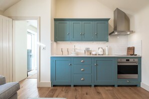 A kitchen with teal cabinets, a stainless steel oven, and a white countertop. - Beautiful One BD Cottage Near Burford (Burford)
