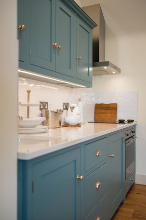 A kitchen with teal cabinets, a white countertop, and a stainless steel range hood. - Beautiful One BD Cottage Near Burford (Burford)