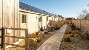 A row of cabins with solar panels, a gravel pathway, and wooden fences. - Beautiful One BD Cottage Near Burford (Burford)