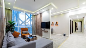 Una sala de estar moderna con sofá, sillón, mesa de centro, televisor y una obra de arte en la pared.