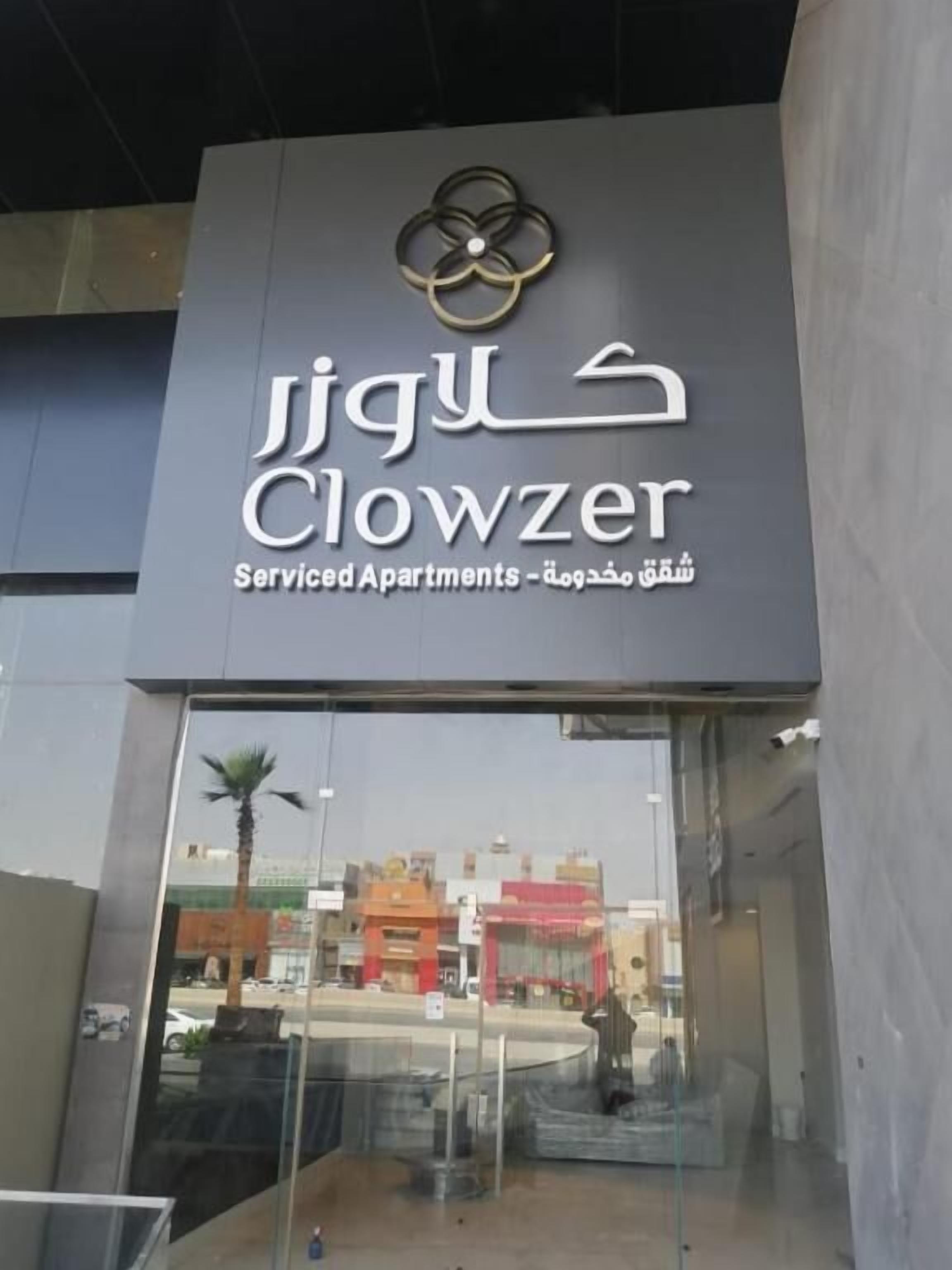 A building with a sign for 'Clowzer Service Apartments' and a logo above the sign.