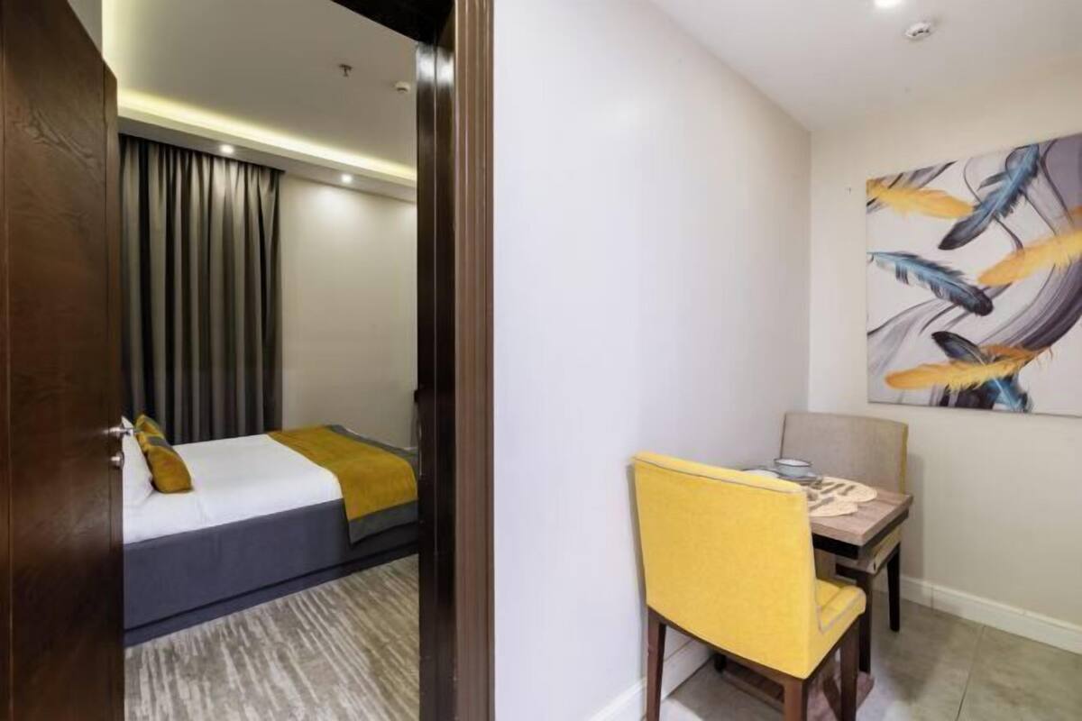 A hotel room with a bed, a desk, a chair, and a painting on the wall.