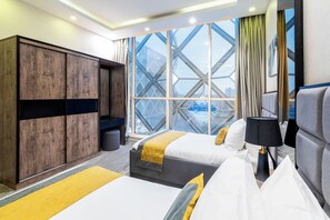 A hotel room with two beds, a wardrobe, a window with a view, and a lamp. - Clowzer Serviced Apartments (Riyadh)
