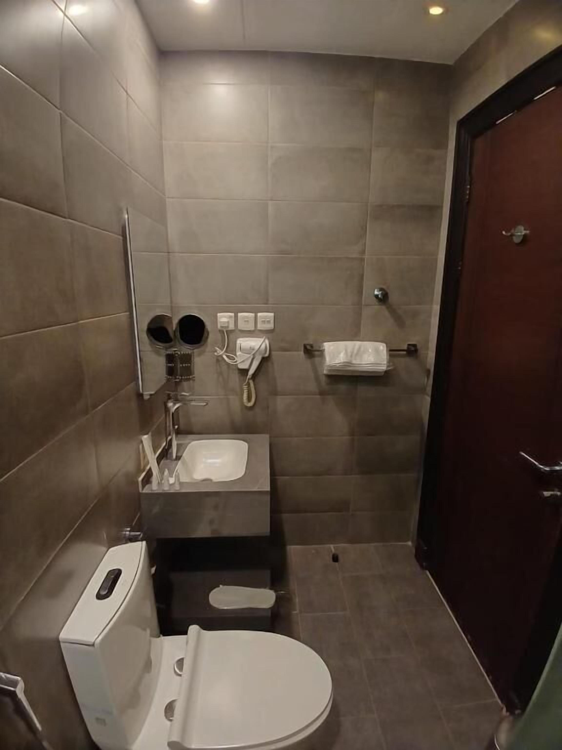 Een compacte, moderne badkamer met toilet, wastafel en spiegel.