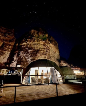 A tented accommodation with a view of a rock formation at night.