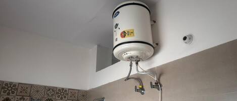 Un escalfador d'aigua fixat al sostre amb una paret de rajoles sota.