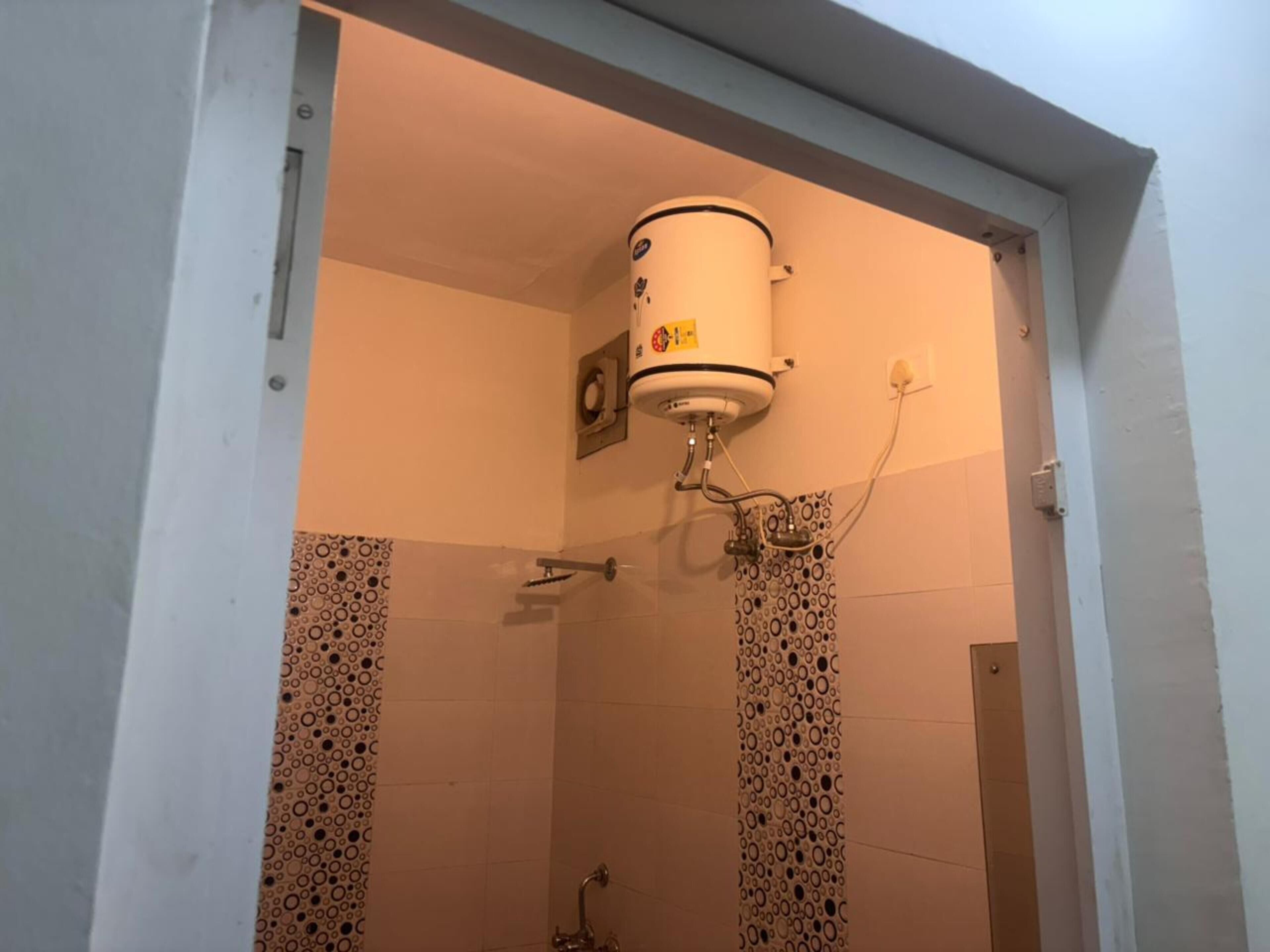 A bathroom with a toilet, a shower, and a wall-mounted heater.