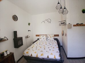 A bedroom with a bed, a wall-mounted speaker, a hanging light fixture, and a wall decoration. - Studio hypercentre hyper calme Argelès-Gazost (Argelès-Gazost)