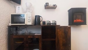Uma cozinha compacta equipada com micro-ondas, cafeteira e chaleira.