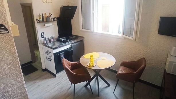 Uma cozinha compacta com área de refeições, máquina de café e televisão na parede.