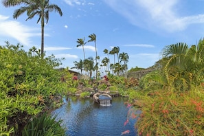Un jardín tropical con fuente de agua, palmeras y abundante vegetación.
