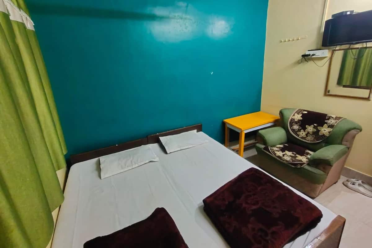 A room with a bed, a small table, a chair, a television, and a wall-mounted air conditioner.