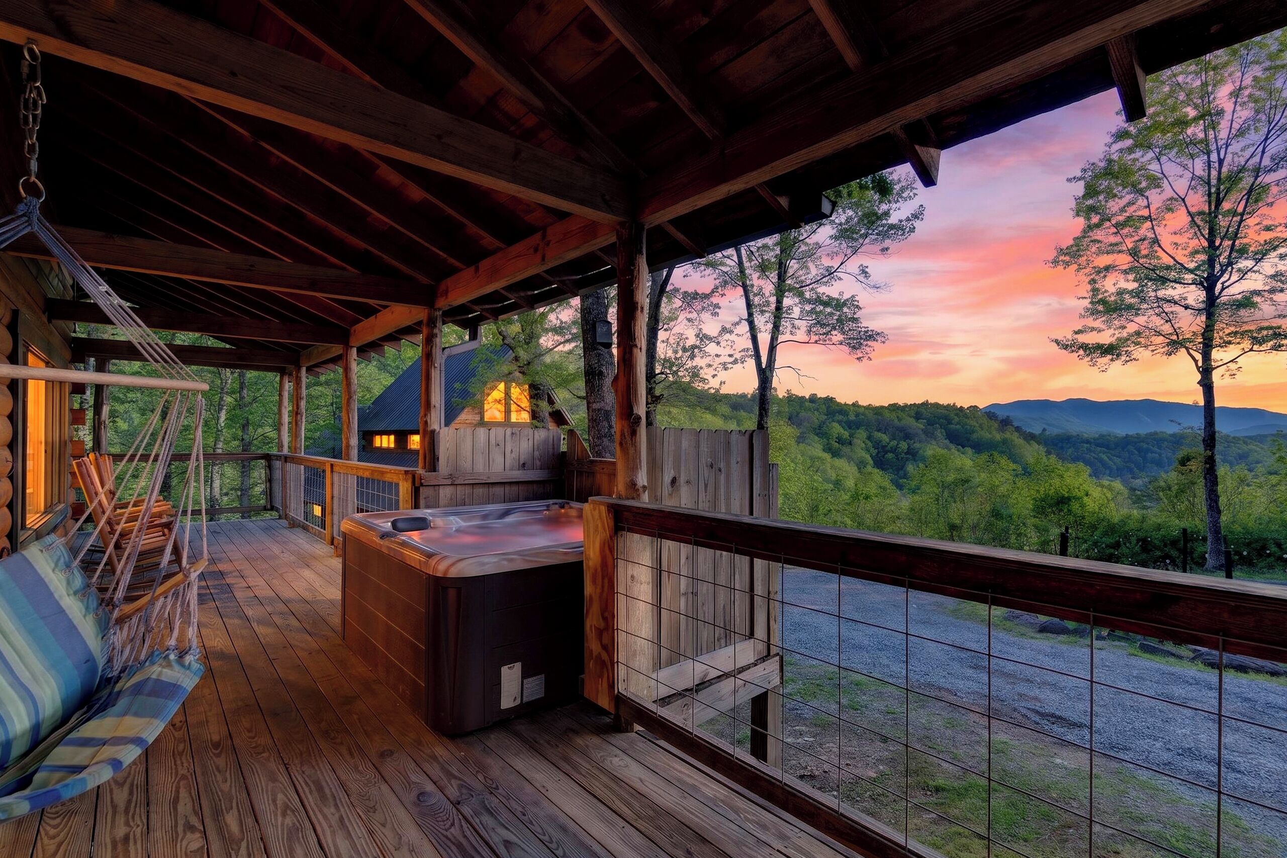 Covered deck with a private hot tub, hanging swing, and stunning Smoky Mountain sunset views.