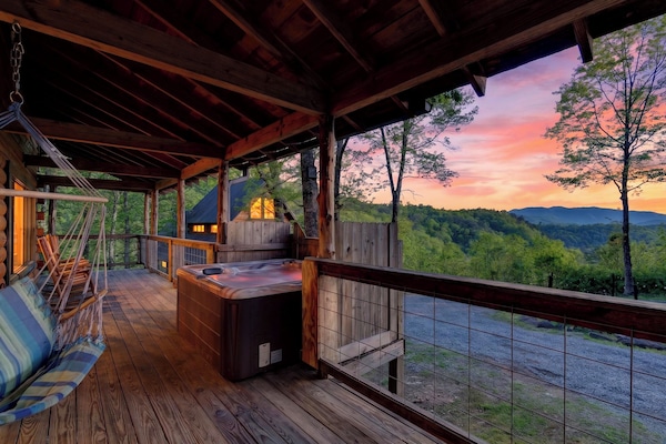 Covered deck with a private hot tub, hanging swing, and stunning Smoky Mountain sunset views.