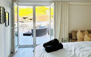 A hotel room with a bed, a sofa, a small table, and a sliding glass door leading to an outdoor area with a patio and a hot tub. - 2BR Apt With 1LR Close to Museum Gugging (Klosterneuburg)