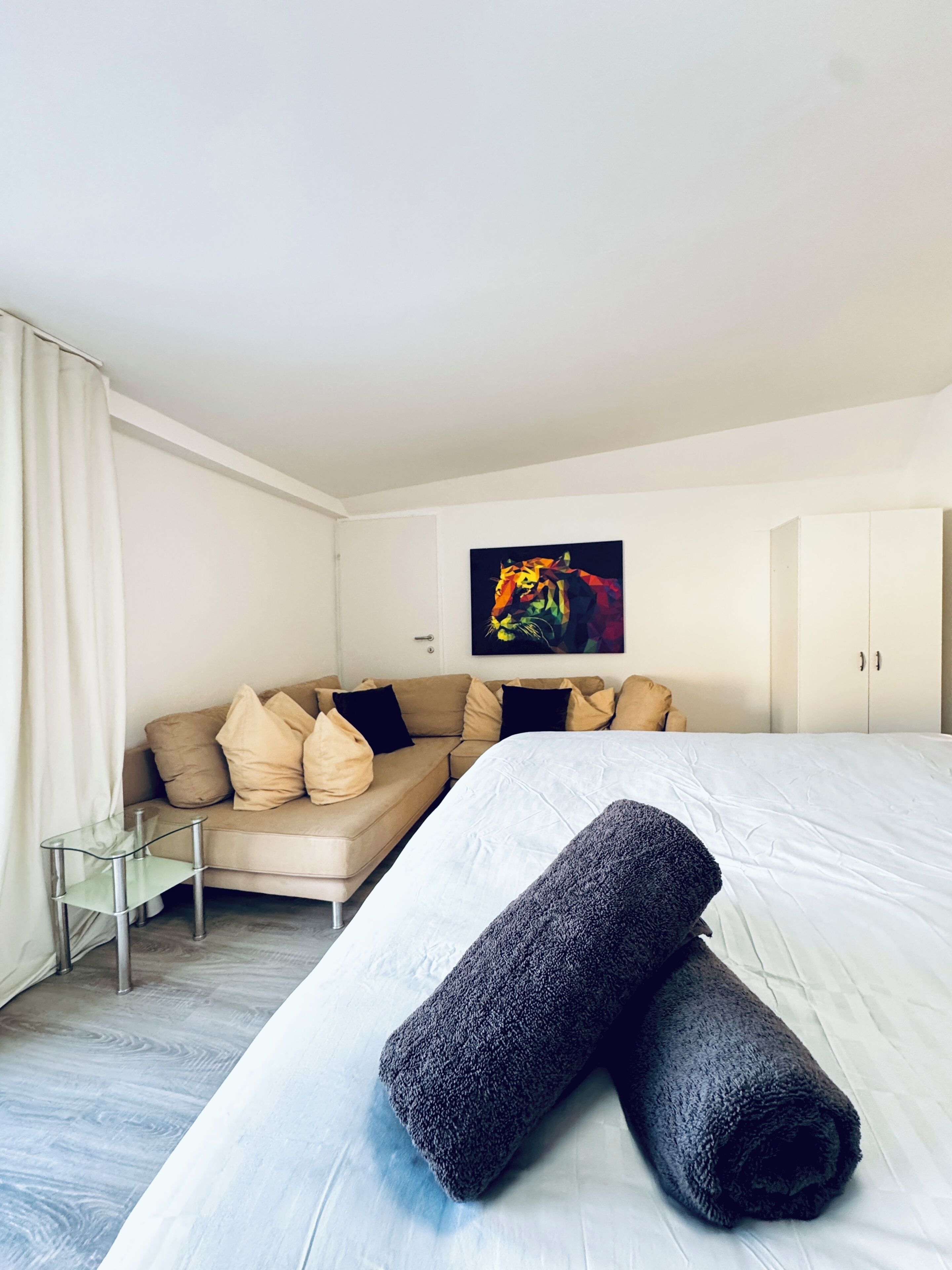 Una habitación de hotel con una cama, un sofá, una mesita de cristal y un cuadro en la pared.