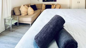 Una habitación de hotel con una cama, un sofá, una mesita de cristal y un cuadro en la pared.
