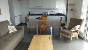 Un salon moderne comprenant un canapé, une table basse en bois et un coin repas avec une table et des chaises.