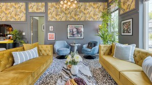 Ein modernes Wohnzimmer mit zwei Sofas, einem Couchtisch mit Blumen und einer Wand mit Muster.